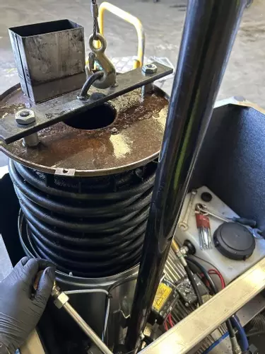 Engineer lifting burst boiler coil out of industrial hot pressure washer during emergency repair in Atherstone.